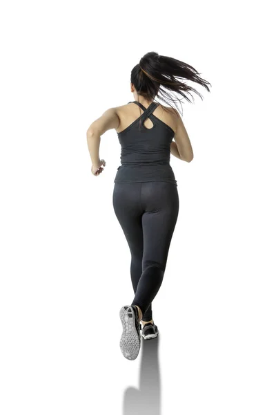 Vista posteriore della donna in abbigliamento sportivo corre in studio — Foto Stock