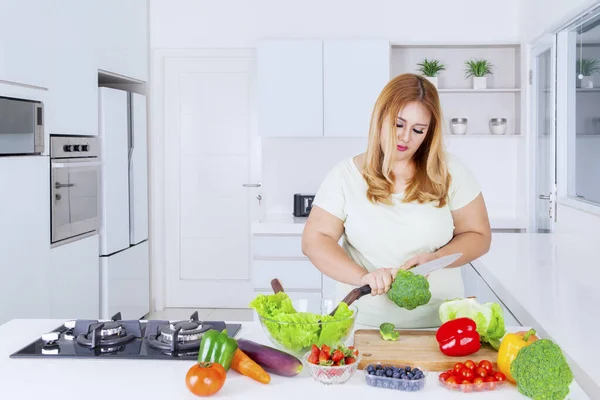 Blond överviktig kvinna skära grönsaker — Stockfoto