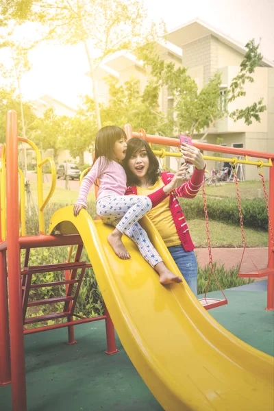 Chica y madre tomando foto selfie en el patio de recreo —  Fotos de Stock