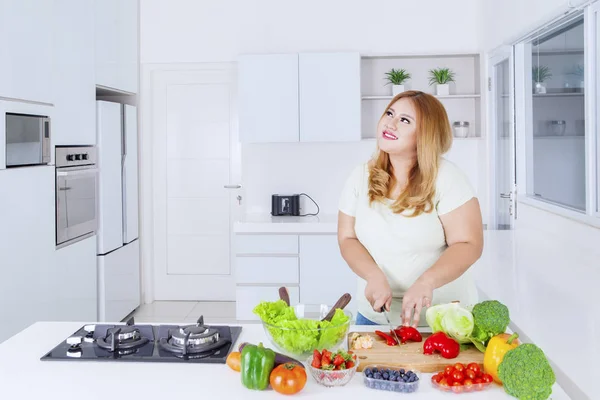 Överviktig kvinna förbereder grönsaker för att göra sallad — Stockfoto