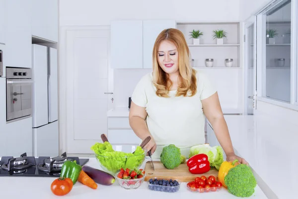 Mulher com excesso de peso preparando legumes para fazer salada — Fotografia de Stock