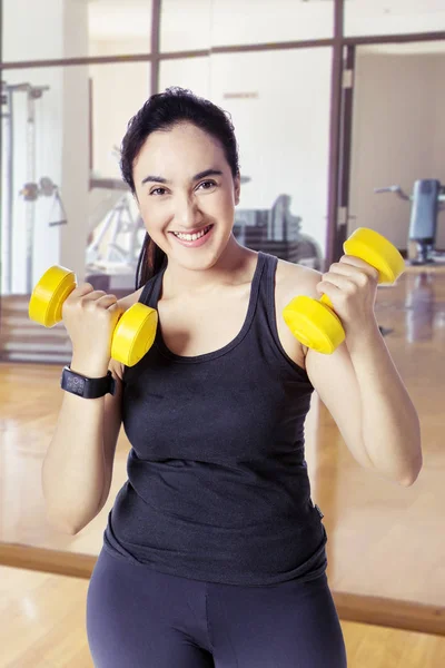 Mujer haciendo ejercicio con pesas mientras sonríe — Foto de Stock