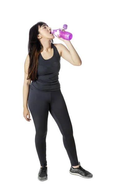 Stüdyoda spor giyinen bir kadın su içiyor. — Stok fotoğraf