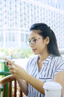 Kafeteryada cep telefonu kullanan bir kadın.