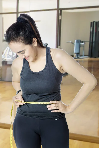 Young woman in sportswear measures waist — Stock Photo, Image