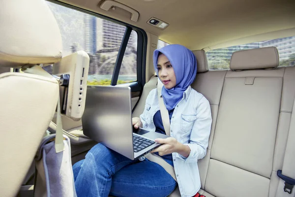 Mujer musulmana trabajando con un portátil en coche — Foto de Stock