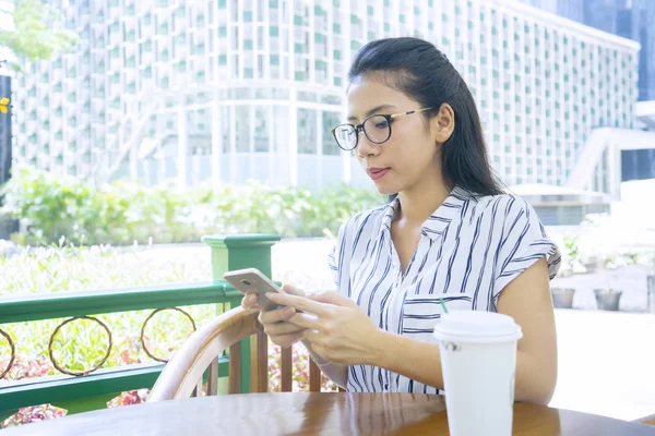 Γυναίκα κάθεται στο καφέ, ενώ χρησιμοποιώντας το κινητό τηλέφωνο — Φωτογραφία Αρχείου