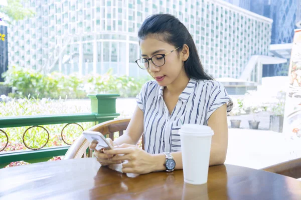 Γυναίκα που χρησιμοποιεί το κινητό τηλέφωνο στο τραπέζι στο καφέ — Φωτογραφία Αρχείου