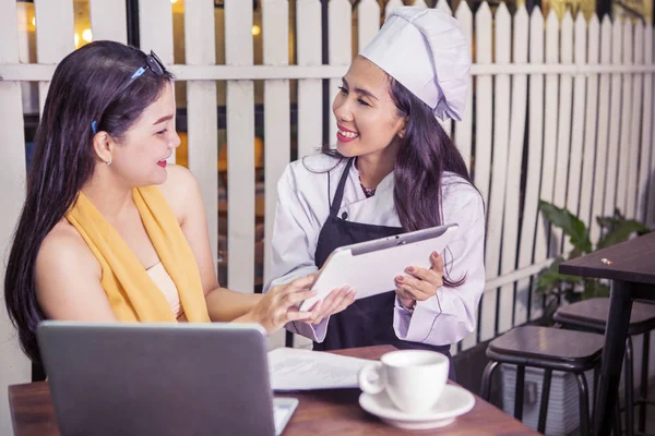 Beautiful waitress serves menu on digital tablet