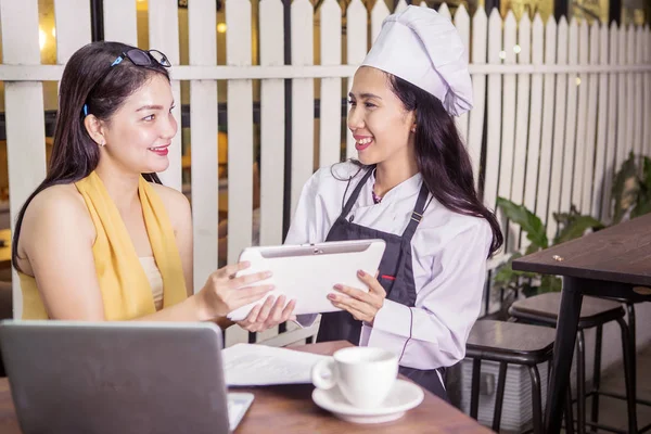 女人和女服务员笑着在咖啡店里放平板电脑 — 图库照片