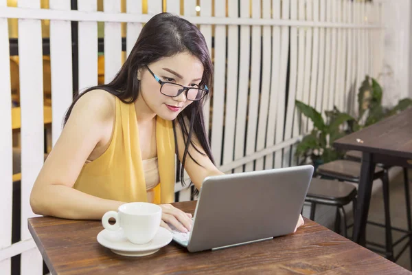 Egy fiatal nő nézi a laptopját a kávézóban — Stock Fotó