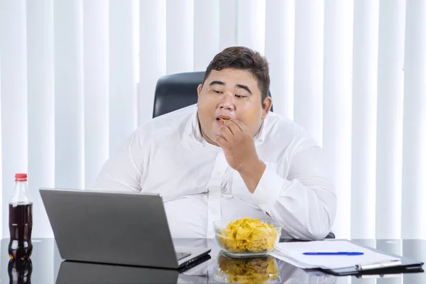 Retrato Gordo Empresario Asiático Comiendo Papas Fritas Mientras Trabajaba Portátil —  Fotos de Stock