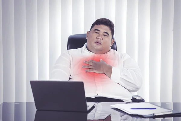 在办公室的笔记本电脑前 一个亚洲胖子脸色苍白地捂着胸膛的画像 — 图库照片