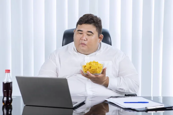 Portrait Fat Asian Businessman Holding Eating Chips While Working His — Stock fotografie