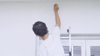 Erkek işçi duvarı boyamak için fırça kullanıyor.