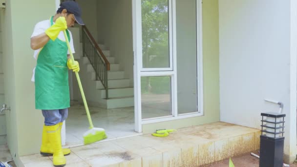 Muž pracovník zametání prašné podlahy terasy domu