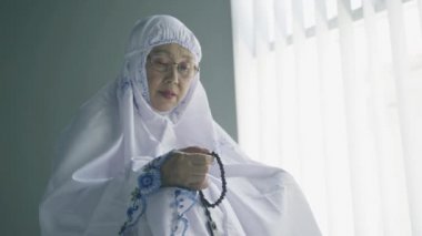 Kıdemli kadın namazdan sonra dhikr için boncuk tutuyor.