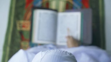 Paspasın üstünde Kur 'an okuyan yaşlı kadının üst görüntüsü