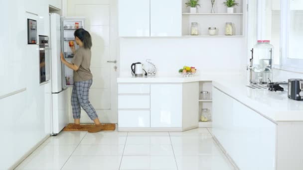 Веселая Молодая Женщина Берет Яблочный Фрукт Холодильник Танцует Дома Кухне — стоковое видео