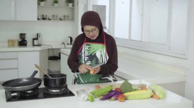 Yaşlı Müslüman kadın sağlıklı bir yemek hazırlıyor.