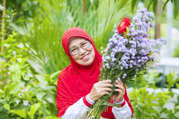 Retrato Alegre Mujer Musulmana Mayor Sosteniendo Flores Sonriendo Cámara Jardín —  Fotos de Stock