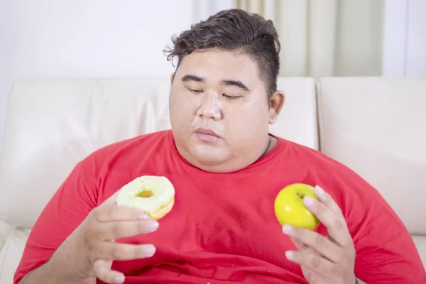 Portrait Fat Asian Man Sitting Couch While Confused Choosing Doughnut — Stock Photo, Image