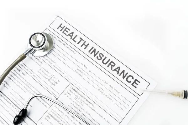 Flat layout of health insurance document paper beneath a stethoscope and a syringe, isolated in white background