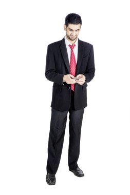 Yakışıklı iş adamının portresi, beyaz arka planda izole halde stüdyoda dururken cep telefonundan mesaj okuyor.