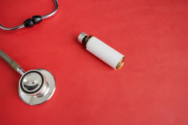 Health and Medicine concept: medical stethoscope and bottle with copy space isolated over red background
