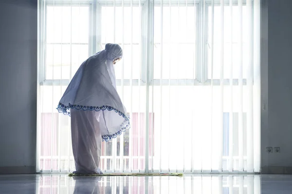 祈りのベールを身に着けている間家で塩をやっている老婦人の写真 — ストック写真