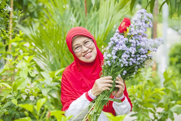 Feliz Mujer Musulmana Mayor Sosteniendo Flores Sonriendo Cámara Jardín —  Fotos de Stock