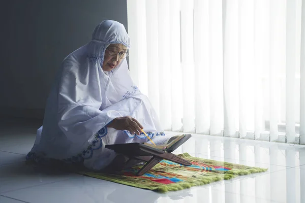 Портрет Пожилой Мусульманки Читает Куран Сидя Молитвенном Коврике — стоковое фото