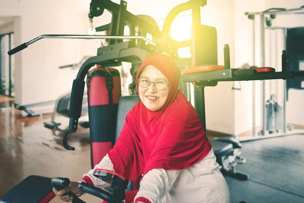 Spor Salonunda Spor Bisikleti Süren Kameraya Gülümseyen Yaşlı Müslüman Kadının — Stok fotoğraf