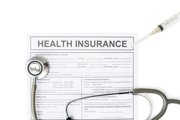 Top down view of health insurance document paper beneath a stethoscope and a syringe, isolated in white background