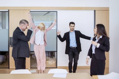 Çeşitli iş adamları toplantı odasında bir tartışmaya katılırken salsa yaparak mutlu bir şekilde dans ediyorlar.