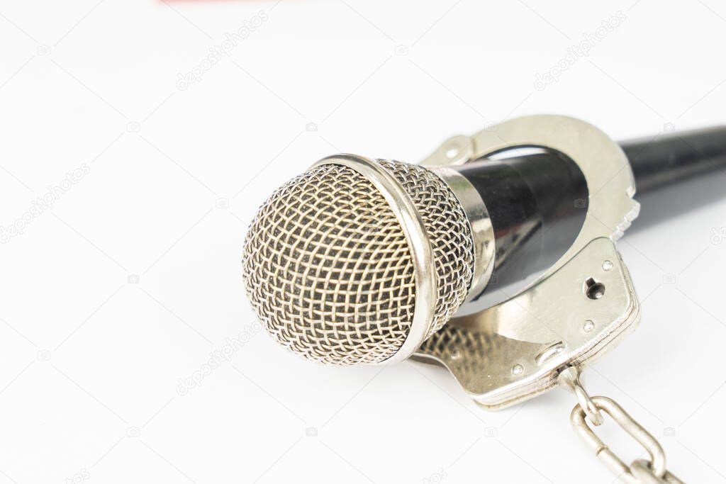 Closeup of microphone with handcuffs, isolated on white background