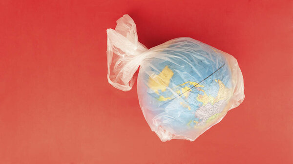 Flat lay of earth globe wrapped in transparent plastic bag.