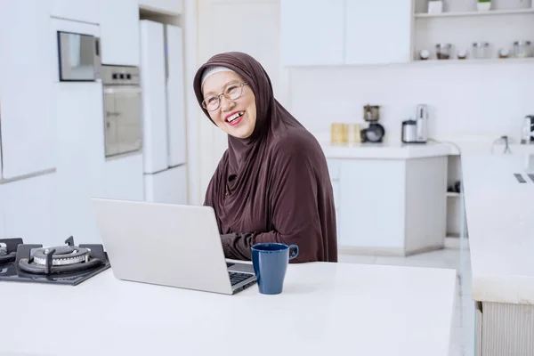 Retrato Mulher Velha Alegre Rindo Enquanto Sentado Com Laptop Cozinha — Fotografia de Stock