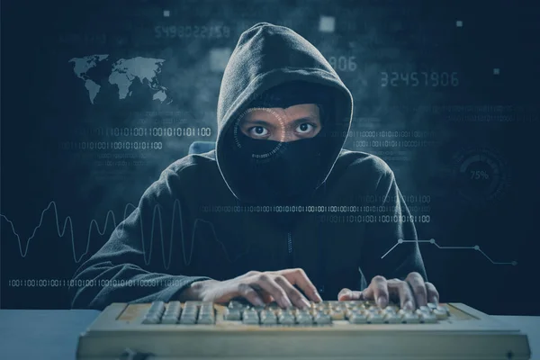 带口罩的黑客使用老式键盘和二进制代码攻击系统 — 图库照片
