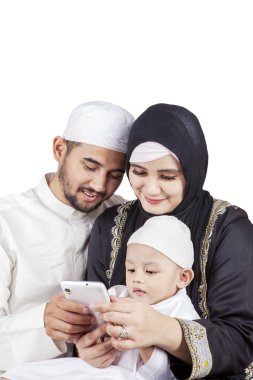 Güzel Müslüman bir aile ve oğulları birlikte cep telefonu kullanıyorlar, beyaz arka planda izole edilmiş.