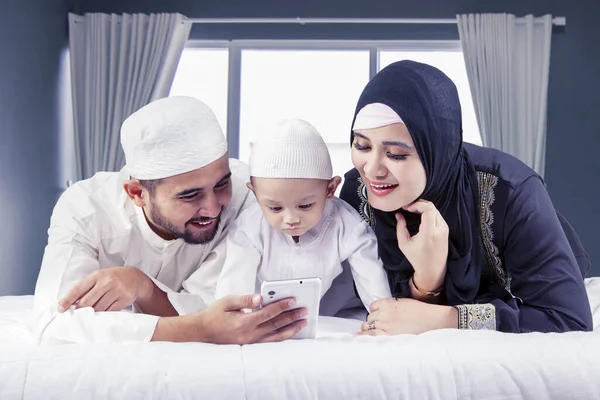 Szczęśliwi Muzułmańscy Rodzice Ich Syn Używają Telefonu Komórkowego Łóżku Domu — Zdjęcie stockowe