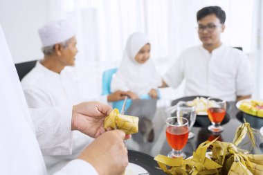Mutlu aile yemek odasındaki bulanık arka planda konuşurken eller ketupa kesiyor.