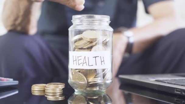 Ouderen Handen Zetten Gouden Munten Een Glazen Pot Met Opschrift — Stockvideo