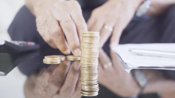 Älterer Mann Stapelt Goldmünzen Mit Taschenrechner Und Dokument Auf Dem — Stockvideo