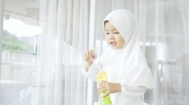 Küçük Müslüman kız sabun köpüğü üflüyor.