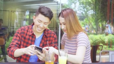 Kafede akıllı telefon kullanan mutlu genç çift.