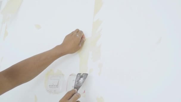 壁から若い男の手は古い壁紙を剥がす — ストック動画