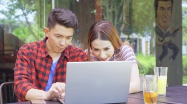 Çekici bir çift sohbet ediyor ve kafede dizüstü bilgisayar kullanıyor.