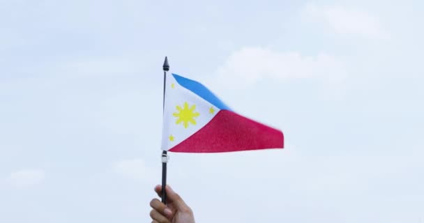 Nieznana Ręka Trzymająca Falującą Flagę Filipin Pod Czystym Niebem — Wideo stockowe