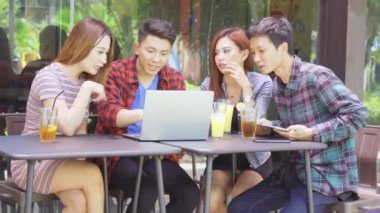 Bir grup genç, kafede dizüstü bilgisayar ve tablet kullanırken birlikte tartışıyorlar.